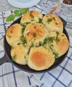 Тарілка з гарячими пампушками з часником, посипаними зеленью