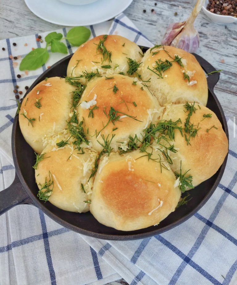 Тарілка з гарячими пампушками з часником, посипаними зеленью