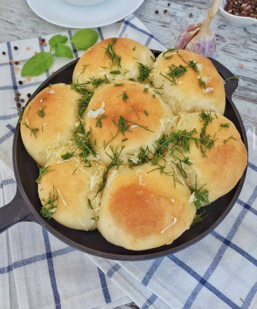 Тарілка з гарячими пампушками з часником, посипаними зеленью