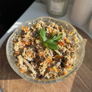 Готовий печінковий салат з курячої печінки, моркви та цибулі у скляному салатнику.