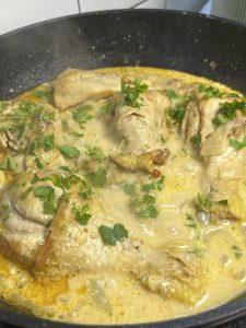Курячі гомілки в сметанному соусі зі свіжою зеленню у сковороді